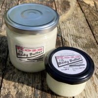 2 clear glass jars, one large, one small, containing body butter.
