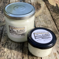2 clear glass jars, one large, one small, containing body butter.